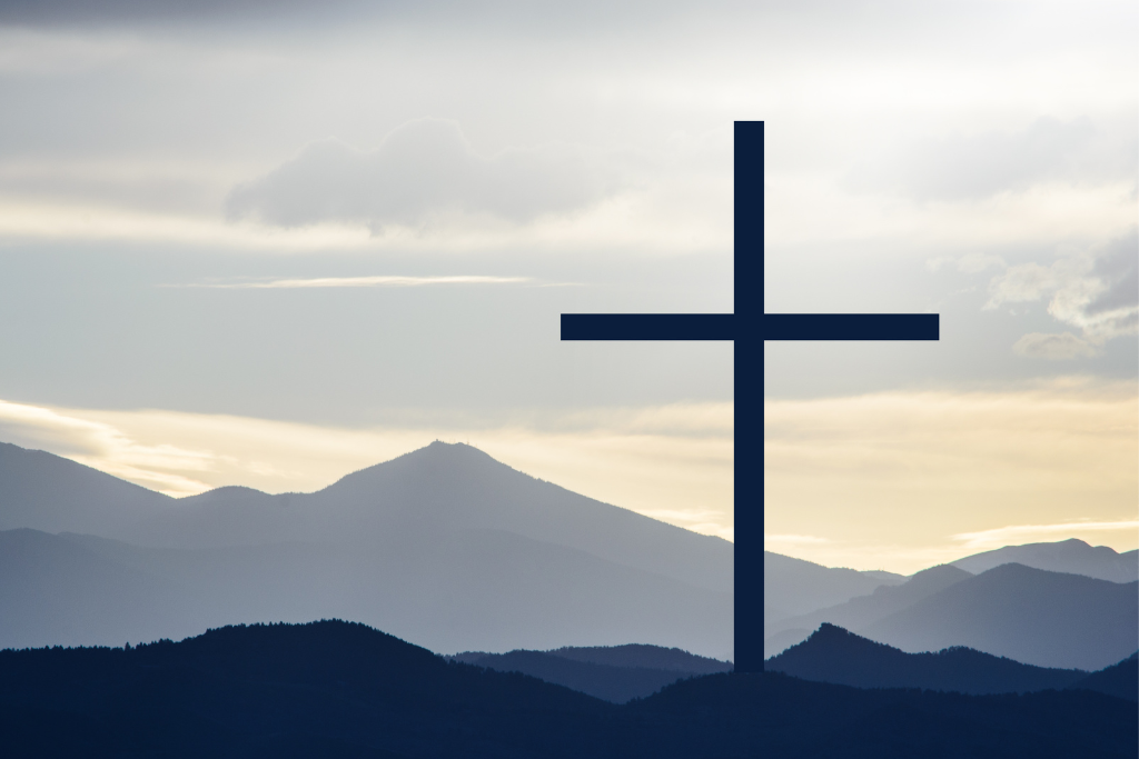 Large cross standing among blue hills and mountains in the background
